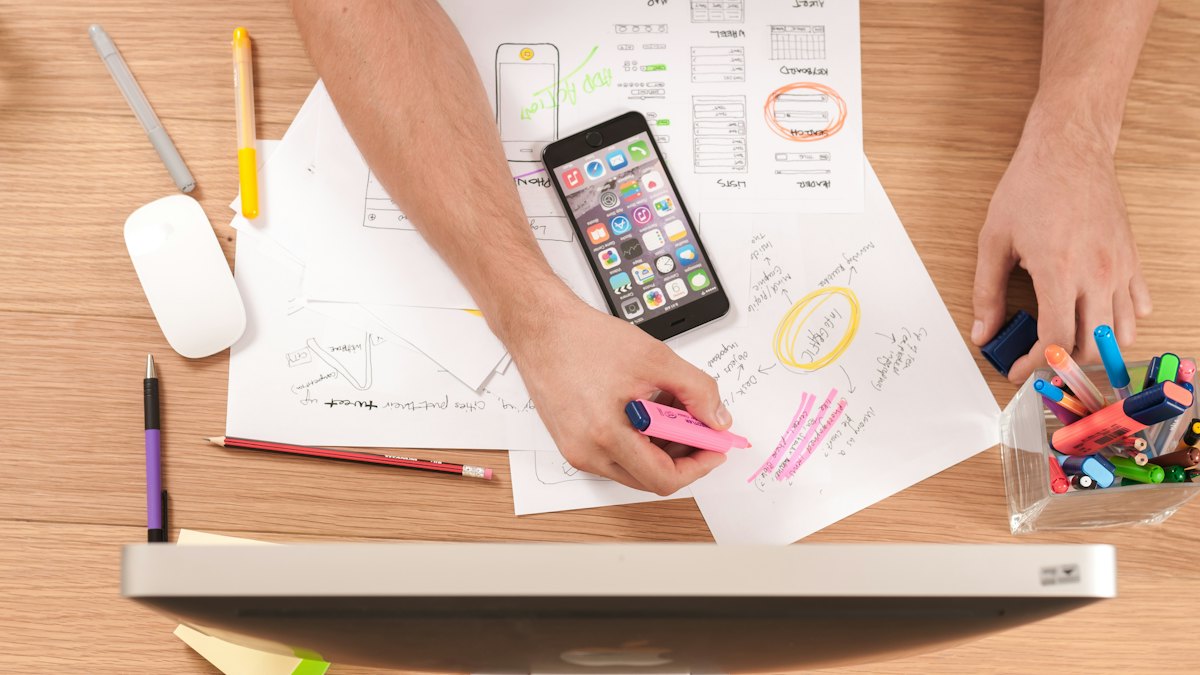 Student planning work at a desk with a phone and notes