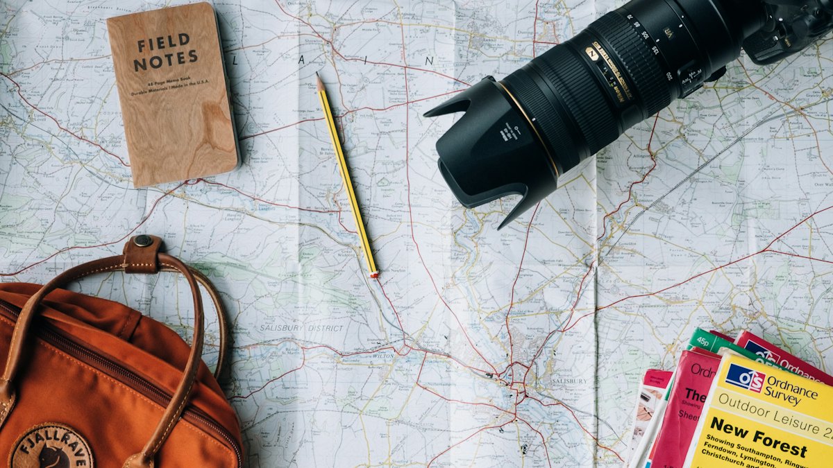 Map, notebook, camera and backpack laid out for a trip