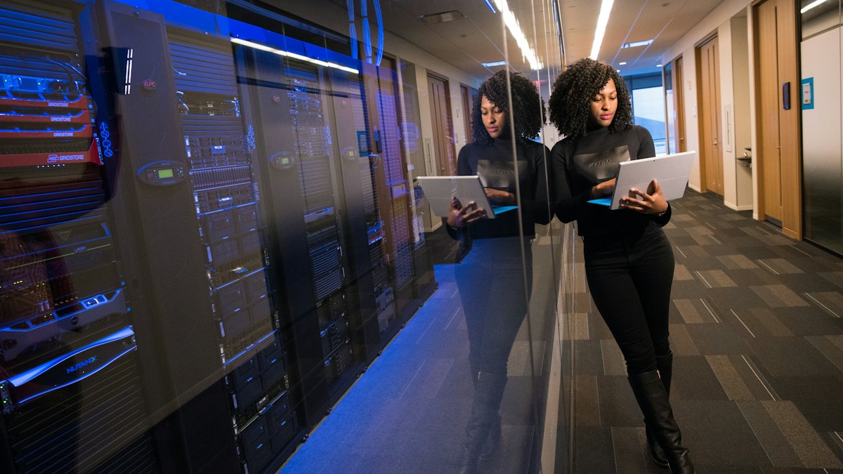 Technician with a laptop walking through a server room