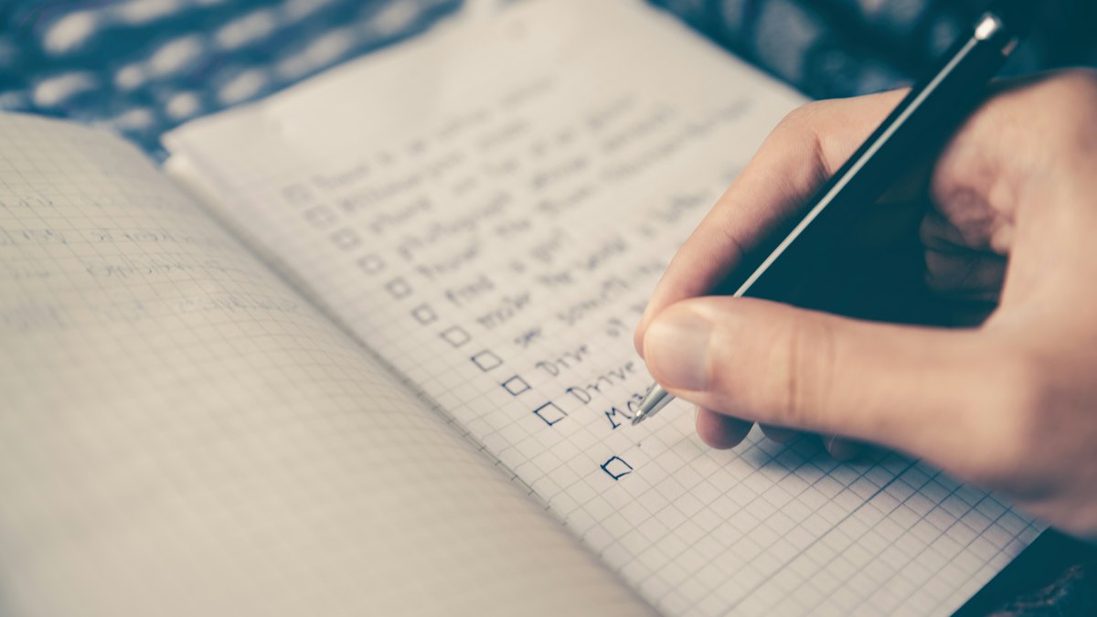 Hand ticking off items on a handwritten checklist