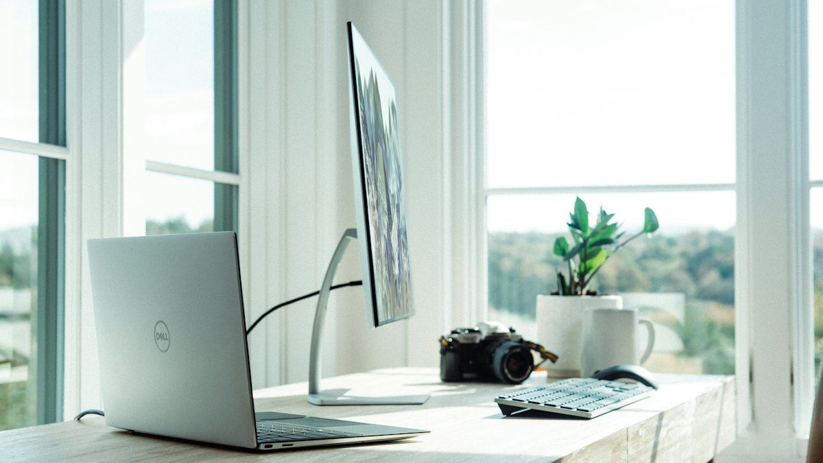 Tidy home office desk with a laptop and a bright window